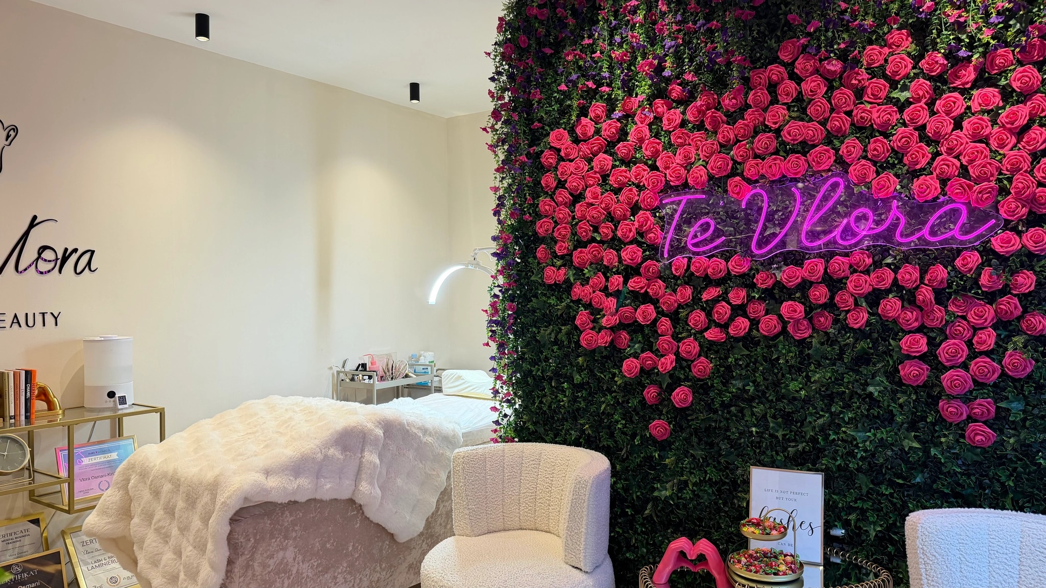 Der Behandlungsraum: Liege, Sessel und die Rosenwand mit dem Neon-Schriftzug